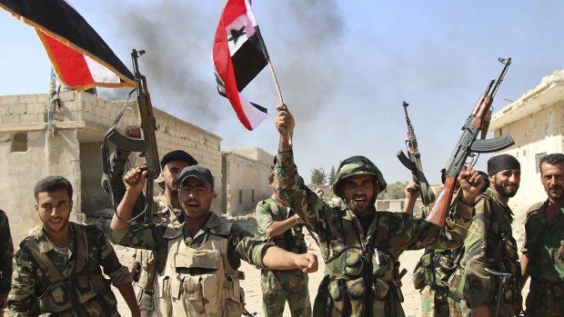 Syrian soldiers wave Syrian flags while celebrating the capture of Achan, Hama province, Syria, on Sunday.
