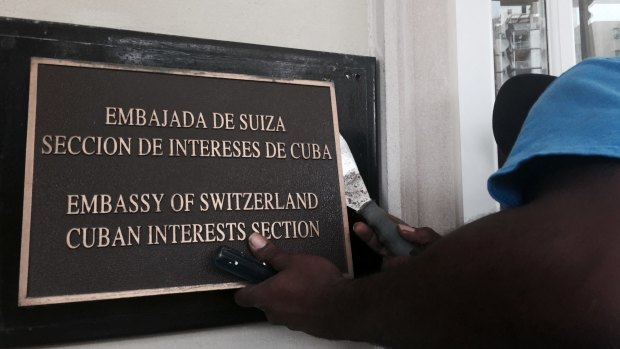 A worker the removes Cuban Interests Section sign in Washington, just days prior to the building being accredited as the Cuban Embassy. 