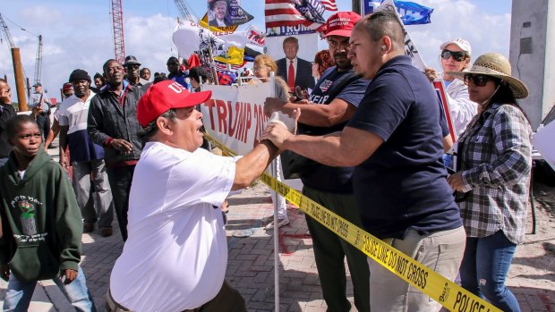 A President Donald Trump supporter, left, confronts a fellow Trump supporter, right, who was speaking on a megaphone, to stop being disrespectful and spewing hate.