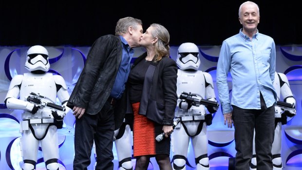 Cast members of the original Star Wars film Mark Hamill, left, and Carrie Fisher kiss as Anthony Daniels looks on during the kick-off event of Disney's Star Wars Celebration 2015 at the Anaheim Convention Centre this year.