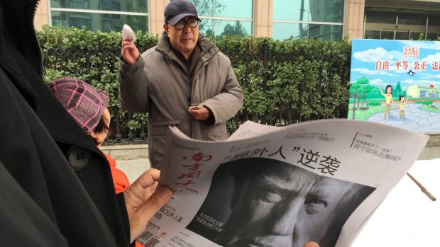 A Chinese man holds up a Chinese newspaper with Trump's photo on the cover.