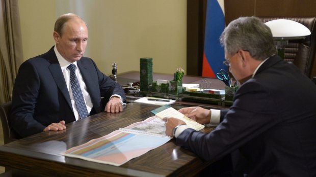 Russian President Vladimir Putin listens to Defence Minister Sergei Shoigu.