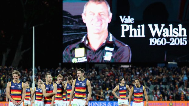 Flood of emotion: Adelaide players walk from the field after round 16 in 2015, as a tribute is paid to coach Phil Walsh. 