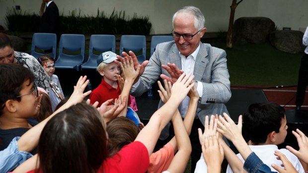 Prime Minister Malcolm Turnbull gives high-fives to children during his visit to the Australian International School in Hong Kong