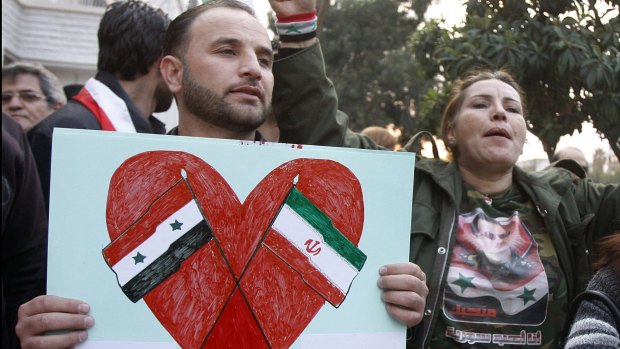 A pro-Syrian regime protester holds a placard showing the Iranian and Syrian flags to thank Iran for its support of the Syrian regime, in Damascus in November.