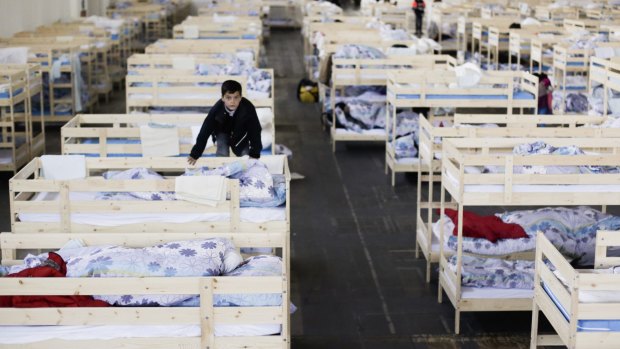 A boy climbs on a bunk bed in a new temporary shelter for migrants and refugees at a hall on the fair grounds in Berlin last week. The hall will have beds for about 1000 people.