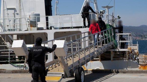 Police lead members of the former whaling vessel's crew away at Hobart in December.