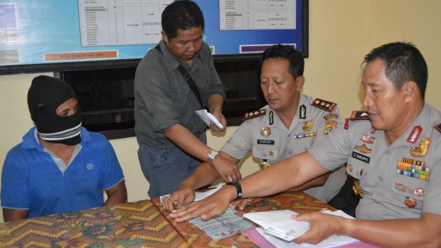 Captain Yohanis Humiang (left) looks on as head of the people smuggling division of Nusa Tenggara Timur, Ibrahim, Rote police chief Hidayat and East Nusa Tenggara Timur police chief General Endang Sunjaya count money in June.