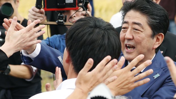 Japanese Prime Minister and leader of ruling Liberal Democratic Party Shinzo Abe, right, greets the crowd in Fukushima, on the first day of campaigning.