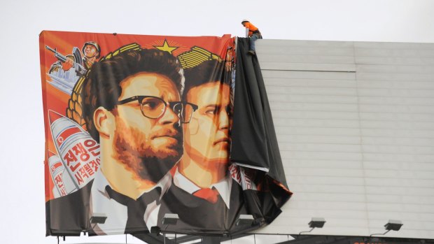 Shelved: Workers remove a poster for <i>The Interview</i> in Hollywood.
