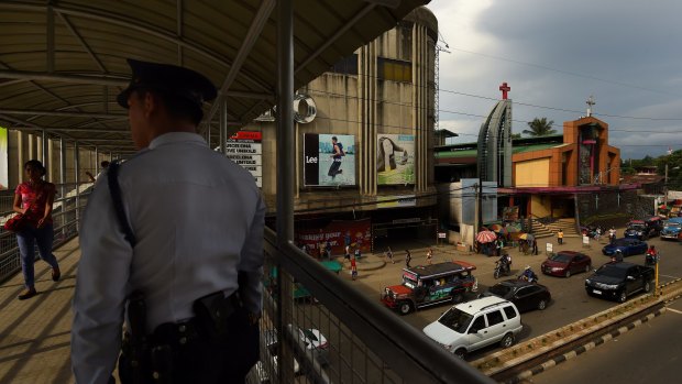 A police officer stands on the overpass connecting two malls in Cagayan De Oro where two of Peter Scully's victims were allegedly groomed by his girlfriend. 