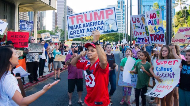 Edward Idquino, center, who holds a Trump Make America Great Again sign confronts a anti-Trump crowd protesting in Honolulu.