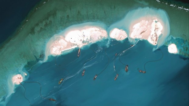 A handout satellite image shows dredgers working at the northernmost reclamation site of Mischief Reef, part of the Spratly Islands, in the South China Sea in March 2015. 