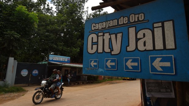 People ride past the Cagayan De Oro City Jail where Australian man Peter Scully is being held. 