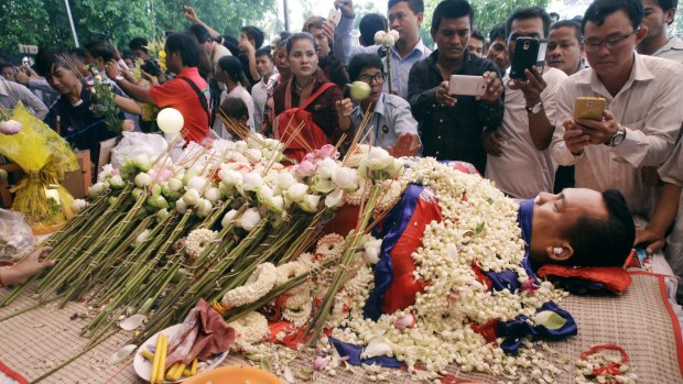 The body of government critic Kem Ley is covered by the Cambodian flag and flowers at a funeral ceremony in Phnom Penh.