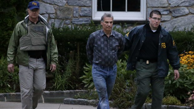 Pastor Vitaly Korchevsky is escorted in handcuffs from his home by agents from the Federal Bureau of Investigation in Glen Mills, Pennsylvania, on August 11. 