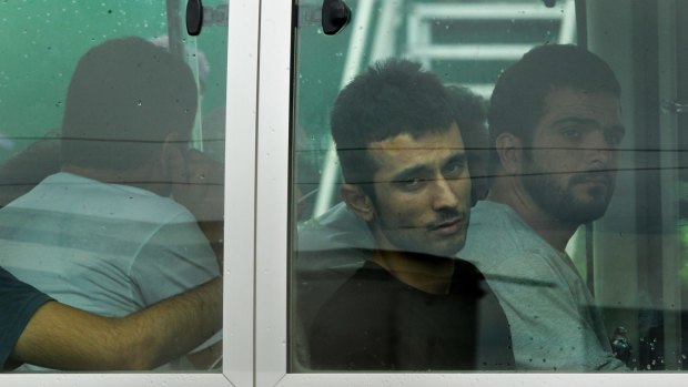 Asylum seekers look out the window of the bus after arriving on Manus Island.