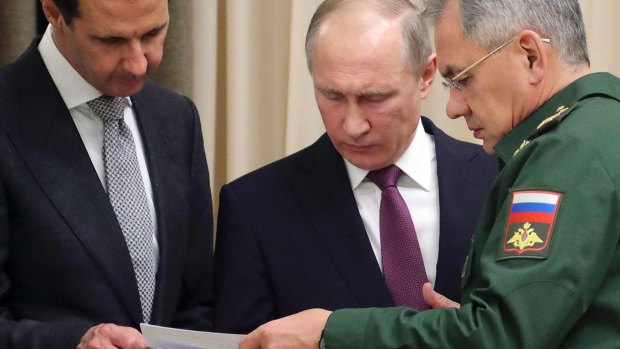 From left: Assad and Putin read a document with Russian Defence Minister Sergei Shoigu in Sochi on Monday.