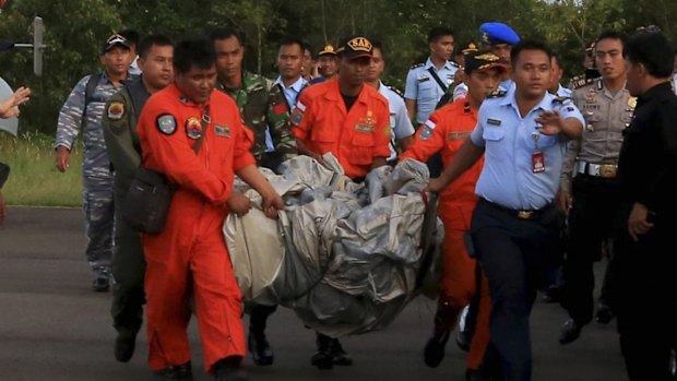 Rescue workers carry debris recovered from the ocean, presumed to be part of the AirAsia plane.