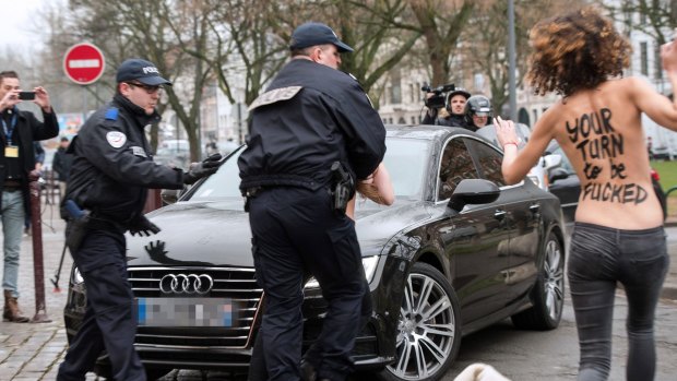 Police detain topless FEMEN activists who jumped in front of Strauss-Kahn's car.