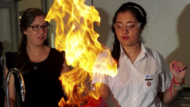 Harrison School year 10 student Zahra
Moinkhah experiences the methane fire bubbles experiment, under
the watchful eye of science teacher Laura Simsen.
