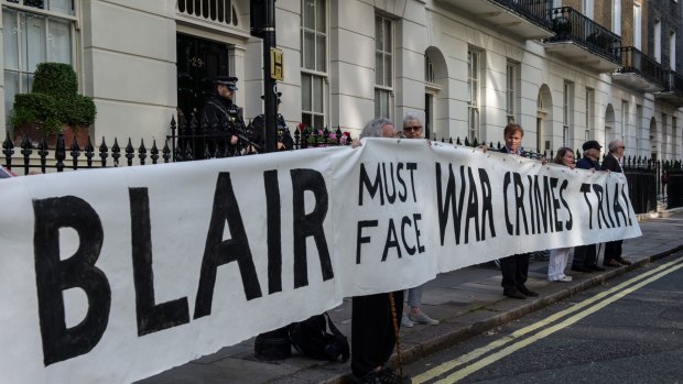 Protesters hold up a banner reading 'Blair must face war crimes trial' outside the London home of former British prime minister Tony Blair on July 6.