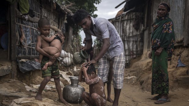 A refugee bathes his child at the Kutupalong  Camp in Teknaaf, Bangladesh.