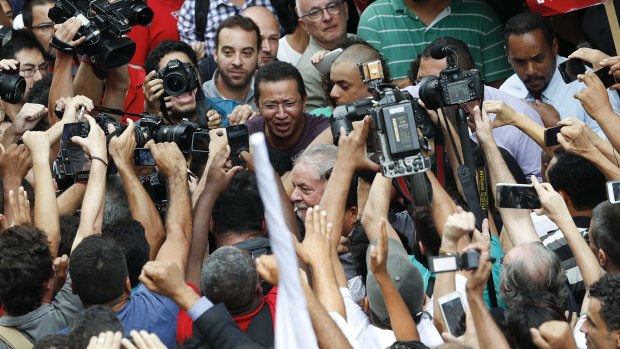 Brazil's former president Luiz Inacio Lula da Silva is surrounded by the press as he walks outside the Workers Party headquarters in Sao Paulo, Brazil, on Friday.