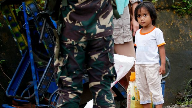 A girl looks at a soldier as people are stopped at a checkpoint in Marawi.