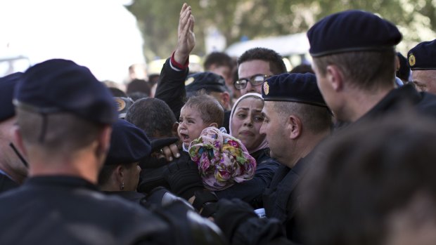 A baby cries as a family tries to push through a police line in Tovarnik, Croatia, on Thursday.