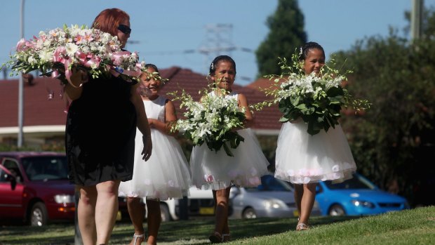 Triplet sisters of Tateolena carry flowers to the funeral.