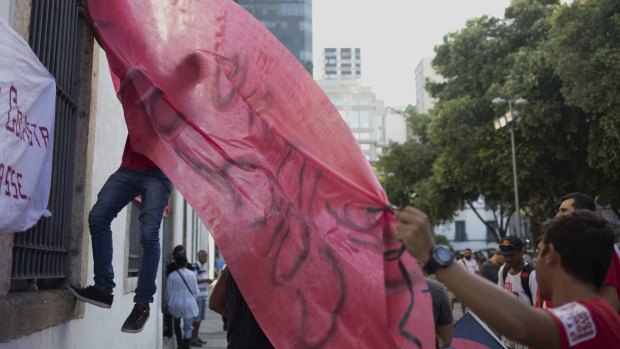 Demonstrators hang a red banner in favour of Dilma Rousseff in Rio de Janeiro on March 18.