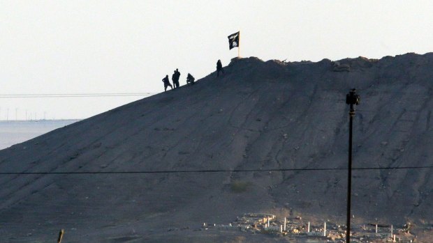 The black flag of Islamic State flies over the town of Kobane in Syria in October 2014.