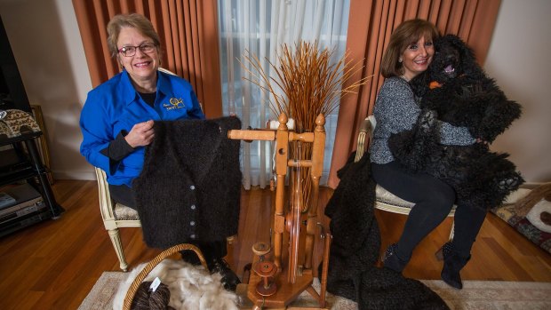 Marion Wheatland (left) holds a vest she spun and knitted from the fur of poodle Mango, held by his owner, May Battista.