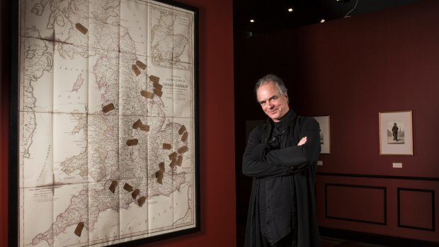 Exhibition curator David Hansen with a map showing where the artist painted many of his subjects.