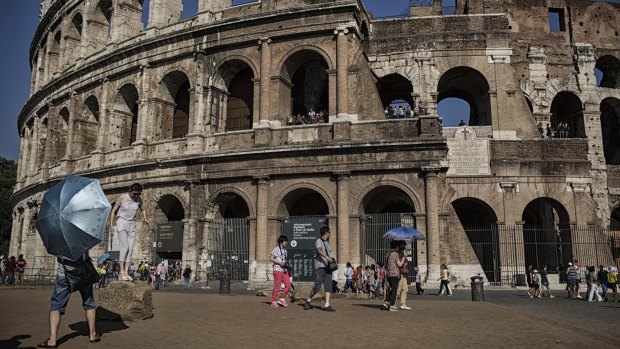 Tourists take photos in front of the Colosseum in Rome this week. 