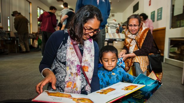 Tazeen Taj with her son Aaqil Ansary, 2, looking through children's books at Tuggeranong Library as part of the ACT's first library sale.