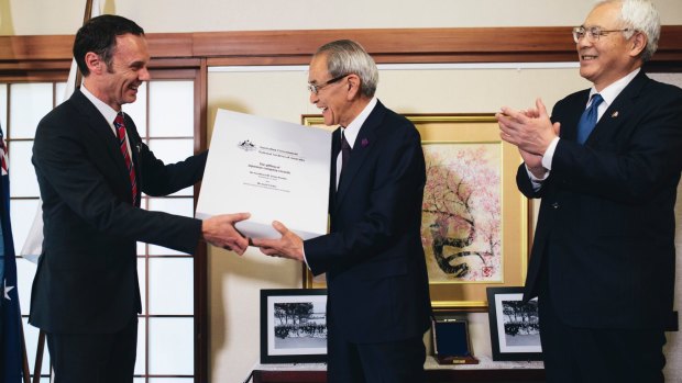 Director-General of the National Archives of Australia David Fricker hands over a box of records to president of the National Archives of Japan Takeo Kato as ambassador Sumio Kusaka watches on.
