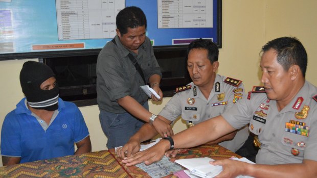 Captain Yohanis Humiang (left) looks on as head of the people smuggling division of Nusa Tenggara Timur, Ibrahim, Rote police chief Hidayat and East Nusa Tenggara Timur police chief General Endang Sunjaya count money in June.