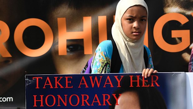 A girl holds a sign calling for the removal of the honorary Canadian citizenship of Myanmar leader Aung San Suu Kyiin Ottawa.