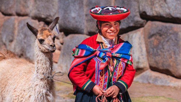 Peruvian girl wearing national clothing walking her llama.