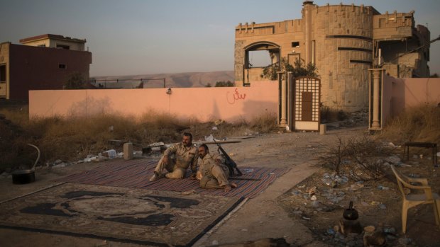 Kurdish Peshmerga fighters rest on the side of the road after taking the city from Islamic State militants in Bashiqa, east of Mosul, on Friday.