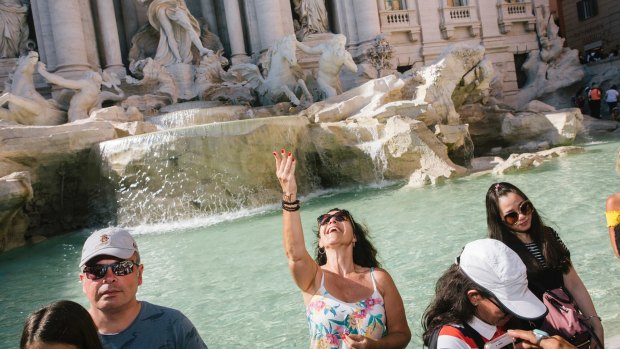 A tourist throws a coin in the Trevi Fountain in Rome.