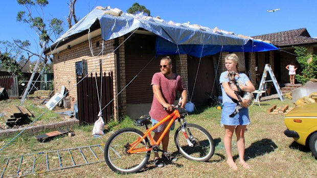 Shane Hendricks and partner Ellie Warner holding pet goat Sassy at the front of his home at 16 Tasman Street Kurnell.