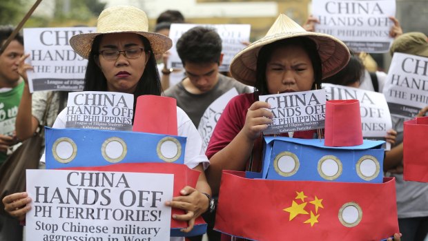 Filipino student activists hold mock Chinese ships to protest recent island-building in the South China Sea.