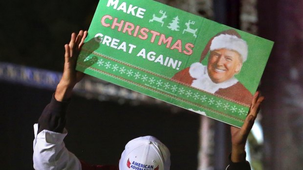 A supporter of President-elect Donald Trump holds up a Christmas-themed sign at a rally in Orlando, Florida.