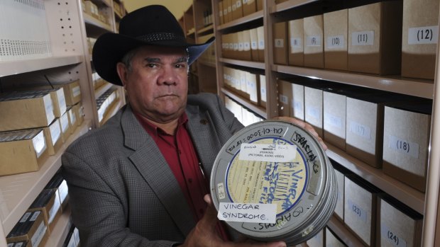 AIATSIS Council chairperson Prof. Mick Dodson with a canister containing a film effected by vinegar syndrome, which can cause dye fading in colour films. 