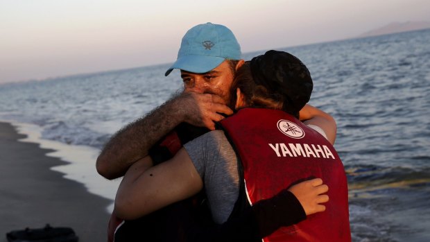 A migrant hugs his family, moments after arriving on a dinghy on the Greek island of Kos, on Tuesday. Nearly a quarter of a million migrants have crossed the Mediterranean to Europe this year, according to IOM. 