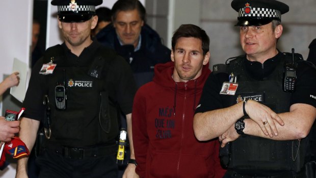 Barcelona's Lionel Messi is escorted by police officers as he arrives at Manchester Airport on Monday.