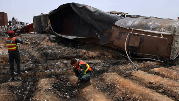 Pakistani rescue workers examine the site of an oil tanker explosion at a highway near Bahawalpur, Pakistan.